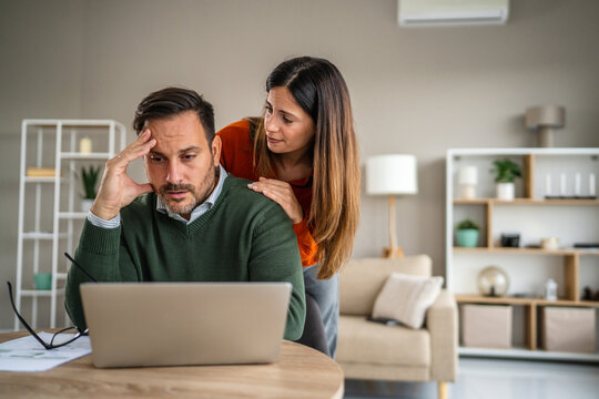 Worried couple discussing finances and managing bills at home