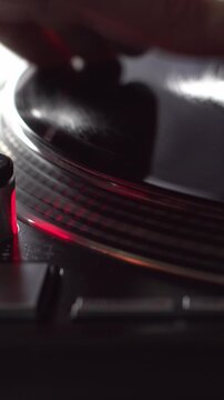 Male hand doing scratch movements on record on turntable. Dj playing music. Vertical footage