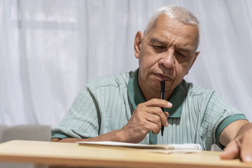 Naklejka premium Routines senior man thinking, contemplating, and writing ideas at home