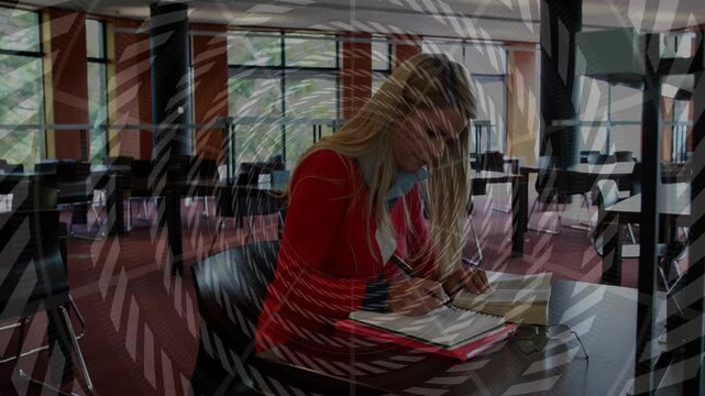 Woman using open book and noting while studying, sitting up as spiral overlay sweeping over her