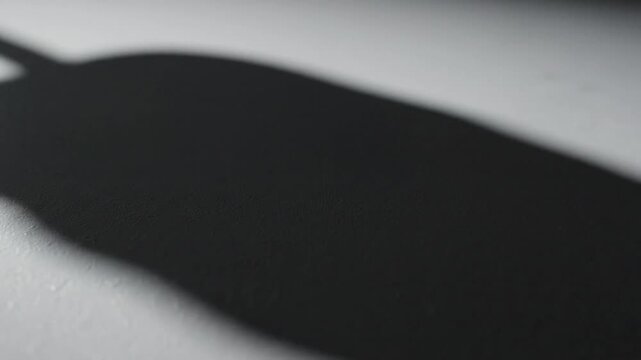 Close-up shot of a black object casting a shadow on a white surface with a shallow depth of field.