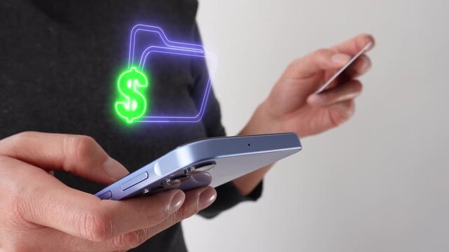 Businesswoman holding a bank card while using a smartphone with a money control document icon. Virtual icon of a folder with a money symbol.