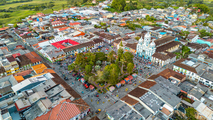 An aerial shot showcasing the vibrant rooftops of Filandia, with a crowded plaza and lush greenery. © Jhampier Giron