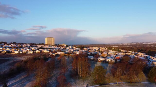 Aerial sunrise view of park leading to suburban houses and imposing DVLA office building in background. Chilly cold winter scene in Swansea, Wales. 4K high quality drone clip.