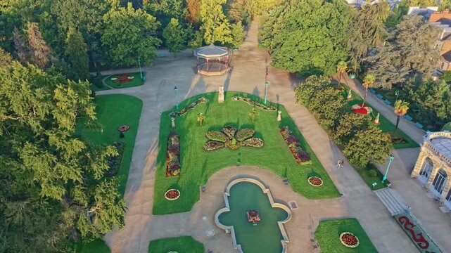 Aerial perspective of landscaped park areas with dense trees and curved walkways in Rennes, Parc du Thabor, orbit fountain