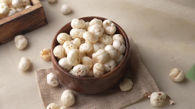 Makhana on wooden bowl closeup shot in zoomin motion through leaves.