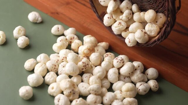 Makhana falling from wooden bowl closeup shot.