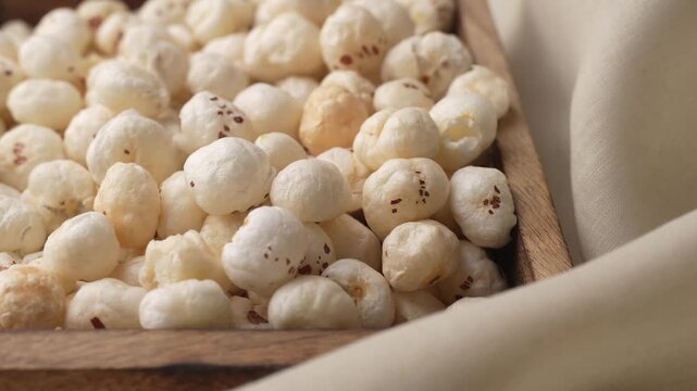 Makhana on wooden tray closeup shot in panning motion.