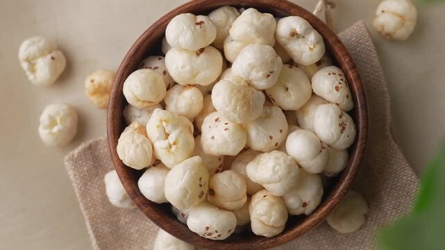 Makhana on wooden bowl closeup shot in zoomin motion through leaves.