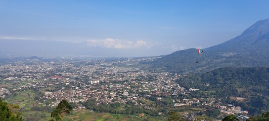 Panoramic view of a town nestled in a valley surrounded by lush green mountains.