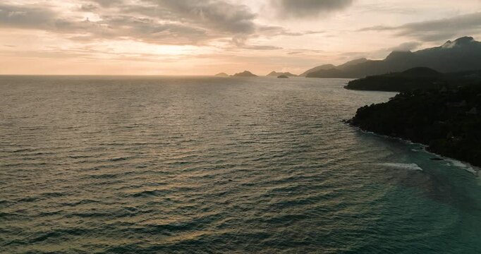 A beachside resort surrounded by dense tropical greenery, facing clear turquoise water. Seychelles, Mahe.
