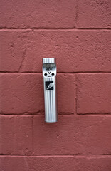 Modern stainless steel cigarette but trash container receptacle mounted to a red brick exterior wall, symbol of a back unhealthy habit
