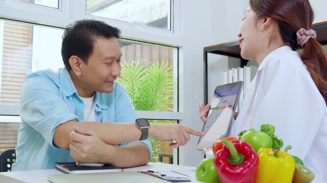 Asian woman nutritionist showing AI BMI calculator on tablet and explaining to man patient, doctor using digital health technology for medical diagnosis, wellness planning and weight control.