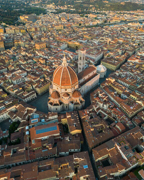 Aerial view of Florence Cathedral illuminated by warm sunset light, showcasing Brunelleschi Dome rising above the historic center of Florence, Tuscany