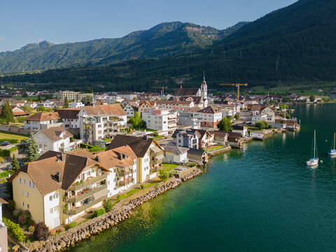 Scenic view of Arth, a lakeside town on Lake Zug in central Switzerland, featuring traditional Swiss houses, clear blue water, and alpine mountains in the background