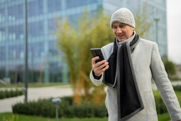 Adult man smiling using smartphone outdoors in city
