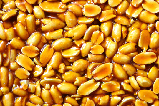 A close up view of golden brown peanut brittle showcasing a dense arrangement of caramelized nuts