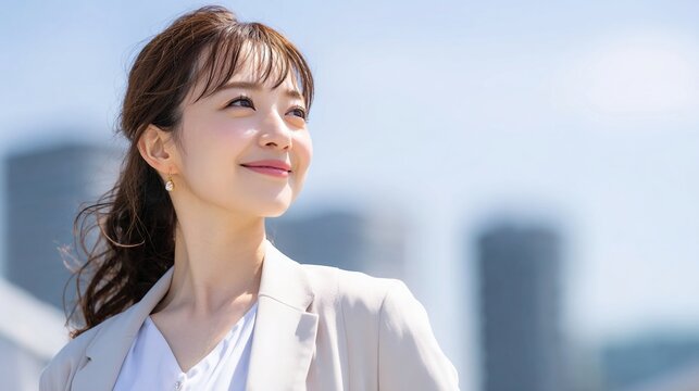 都会の青空の下で成功を確信する日本人ビジネスウーマン