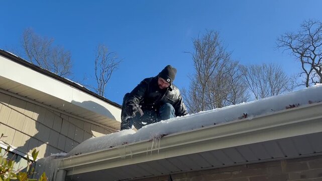 Man Chisels off Frozen Gutters from Ice Dam to Prevent Roof Damage
