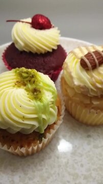 An Assortment of Cupcakes with Various Flavors Spinning on a Plate. High Angle Close Up Vertical Video