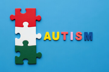 Fototapeta premium Autism text with colorful letters and connected puzzle pieces on blue background symbolizing awareness