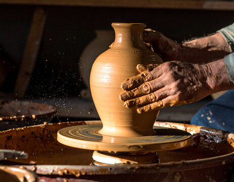 Textured close-up of artisan hands shaping smooth clay on a pottery wheel with soft cinematic lighting, artisanal craft concept