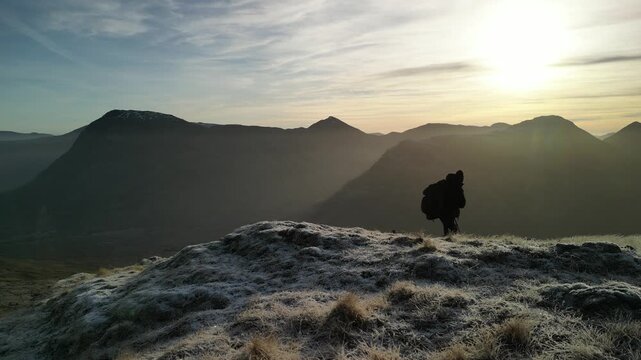 Glen Coe, Scottish Highlands - aerial over the mountains in winter with hill walker hiking through frame - tracking shot