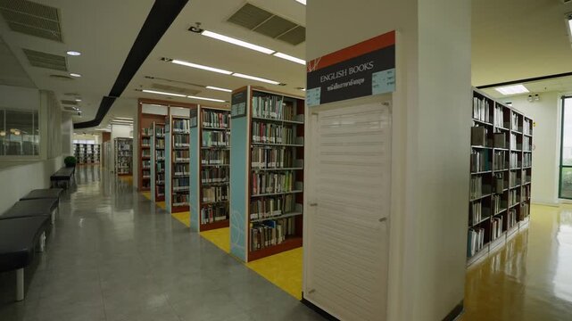 Interior of a university library with bookshelves arranged in rows at a university in Bangkok, Thailand.
