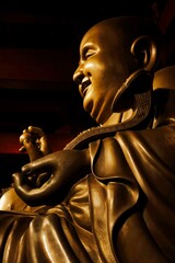 A golden Laughing Buddha statue sits in temple