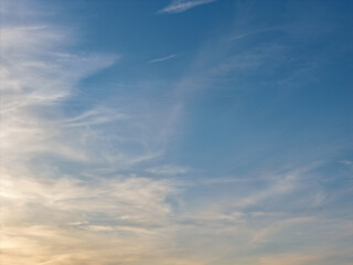 Fototapeta premium Cirrus clouds streak across a gradient sky, forming delicate, wispy patterns and warm evening tones over a calm horizon at plum beach point drive, port washington, ny