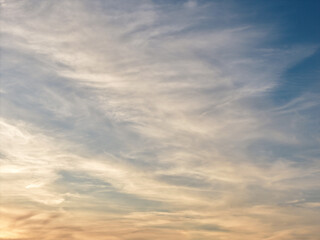 Obraz premium Sky showing wispy cloud formations during a sunset, creating a gradient from blue to soft orange and yellow hues, capturing atmospheric beauty over port washington, new york