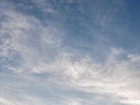 Expansive blue sky featuring delicate, wispy cirrocumulus clouds gracefully drifting across the expansive atmosphere, creating a soft and textured natural background