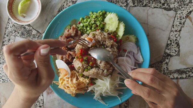 Traditional Thai dish Khao Kluk Kapi made with shrimp paste fried rice served with pork egg and vegetables captured from overhead view