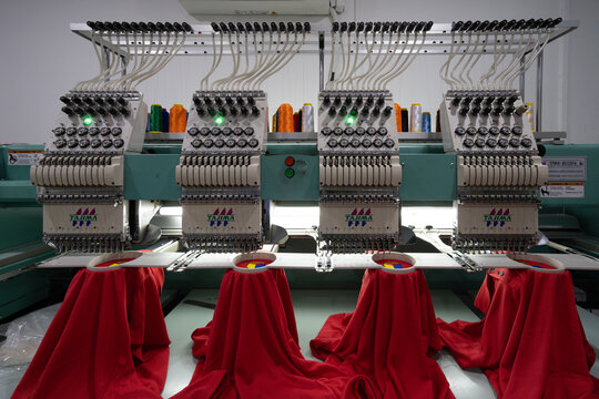 Tajima multi-head embroidery machines embroidering logos on red t-shirts in garment factory