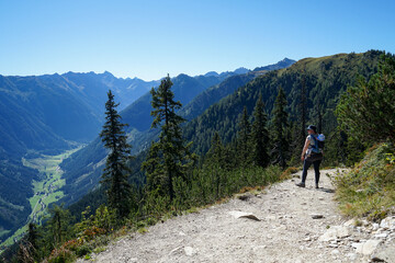 Fototapeta premium Young Mother Hiking with Child in Backpack Enjoying View of Schladming, Austria – Sunny Summer Day with Copy Space