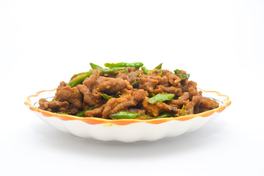 Side view of Indonesian spicy stir-fried chicken intestines (oseng usus ayam) with green chili served on a decorative plate against a clean white background.