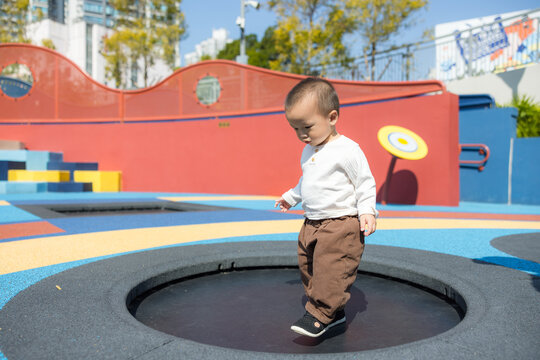 Baby jumping happily on trampoline at park