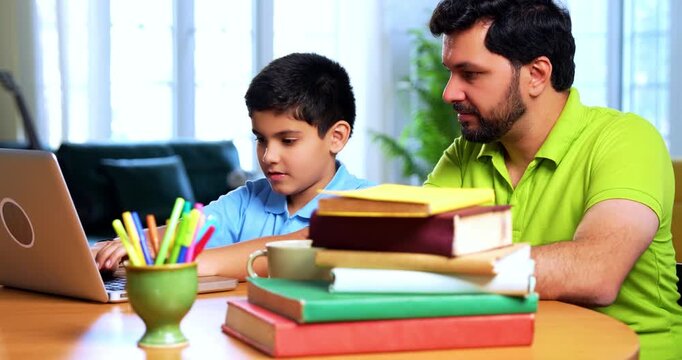 Indian asian kid cracks online exam on laptop while father rejoices sitting beside him at desk during digital test result celebration in cozy modern home interior