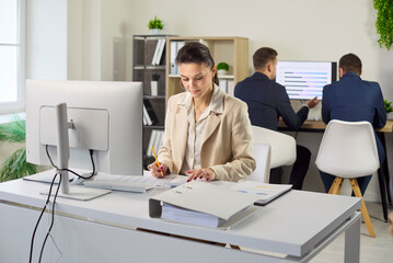 Plakat Accountant conducts audit and analysis on computer. In an office the business woman reviews paperwork and a report while entering data into spreadsheets. Concept of finance audit and teamwork.