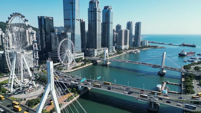 Urban skyline aerial view with ferris wheel and bridge over ocean