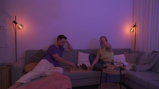 Couple Playing Chess Together on Sofa During Cozy Evening at Home