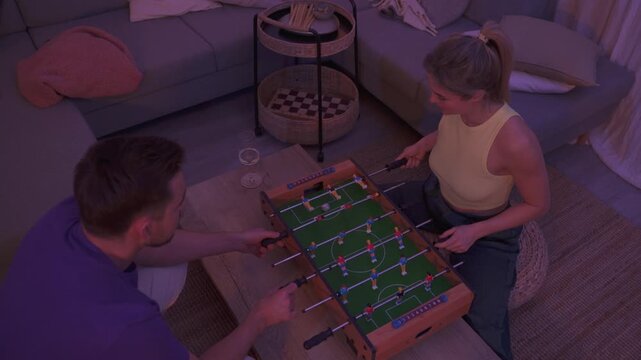 Happy Couple Playing Tabletop Foosball Together in Cozy Living Room