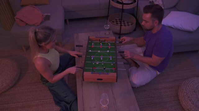 Happy Couple Playing Tabletop Foosball Together in Cozy Living Room