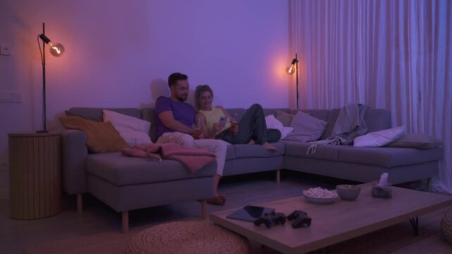  Couple Sitting on Couch with Drinks and Smartphone During Cozy Evening at Home