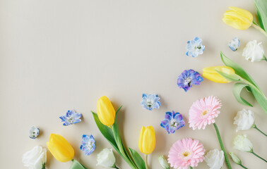 Beautiful spring banner with delicate flowers on pastel table top view. Greeting card for International Women Day or Mother day. Flat lay.