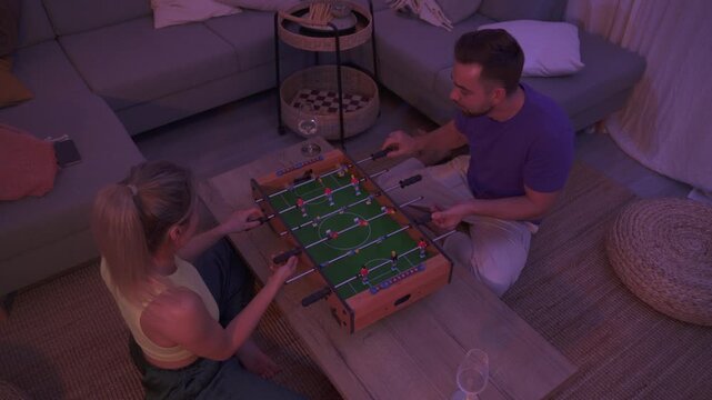 Happy Couple Playing Tabletop Foosball Together in Cozy Living Room