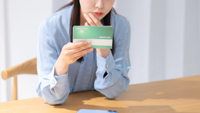 通帳を見て悩む女性