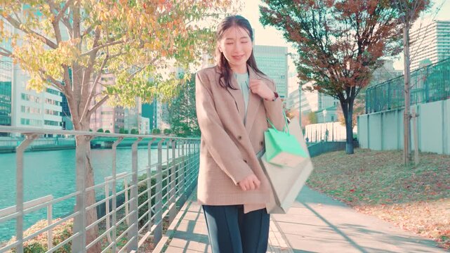 紙袋を持って歩く女性