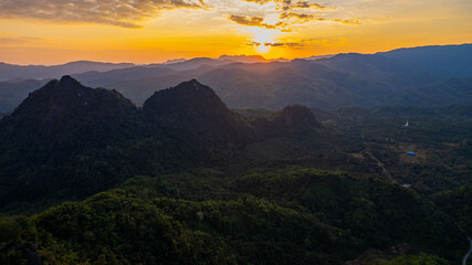 Breathtaking sunset view amidst a backdrop of rolling mountains and lush forests in Thailand