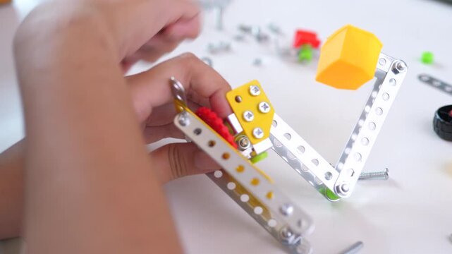 Close up of child hands assembling 3D printed robot model on table. Concept of STEM education, robotics learning, creativity, and technology development